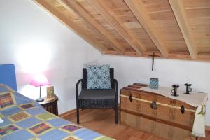 a bedroom with a bed and a chair and a trunk at Casinha de Muda da Feteira in Angra do Heroísmo