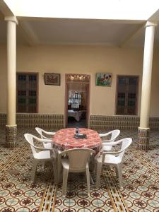 a room with a table and white chairs in a room at Écologie oasis tafilalt CHEZ L' HABITANT in Er Rachidia