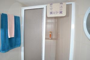 a shower door in a bathroom with blue towels at Casinha de Muda da Feteira in Angra do Heroísmo +33 photos