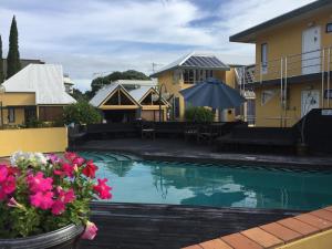 a swimming pool in front of a house with flowers at Bucklands Beach Waterfront Motel in Auckland