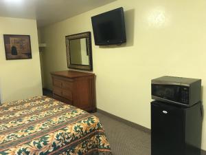 Habitación de hotel con cama y TV en la pared en Hacienda Motel, en Escondido