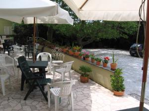 a patio with white chairs and tables and an umbrella at Hotel Naviglio in Marina di Pietrasanta