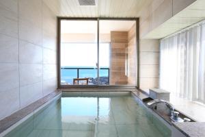 La salle de bains est pourvue d'une piscine avec une grande fenêtre. dans l'établissement Shiosai Resort Kamogawa, à Kamogawa