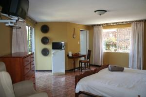 a bedroom with a bed and a refrigerator and a table at Columbus Guest House in Nelspruit