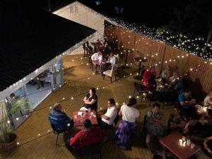 een groep mensen die op een terras met lichten zitten bij The White House Hotel in Apia