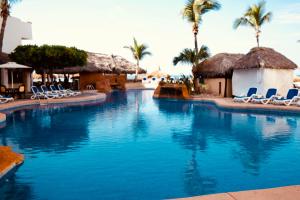 einen großen Pool mit Stühlen und Palmen in der Unterkunft Maz4you Beachfront Condo in Mazatlán