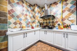 a kitchen with white cabinets and a tiled wall at Chengdu Qingyang·Kuanzhai Alley· Locals Apartment 00170590 in Chengdu +14 photos