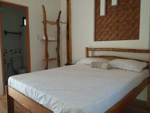 una camera da letto con un letto grande con lenzuola bianche di Sand 1 Hostel a Siquijor