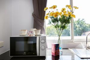 a vase of yellow flowers sitting on top of a microwave at YaYa B By Briza Group in Chalong