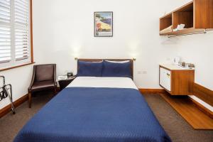um quarto com uma cama azul e uma secretária em Pier Hotel Coffs Harbour em Coffs Harbour