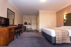 ein Hotelzimmer mit einem Bett, einem Schreibtisch und einem TV in der Unterkunft Sleepwell Motel in Albany