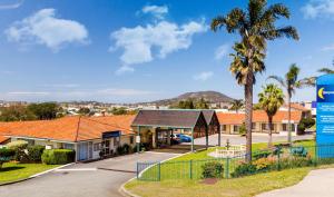 奥尔巴尼逸致汽车旅馆的一排种有棕榈树的房屋和一个停车场