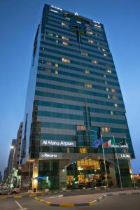 a tall building with a sign on the side of it at Al Maha Arjaan by Rotana in Abu Dhabi