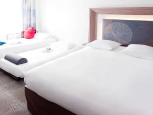 a row of white beds in a hotel room at Novotel Lille Aéroport in Lesquin