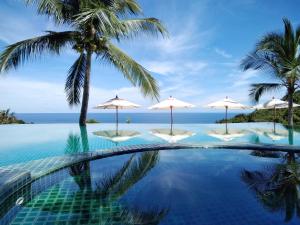 uma piscina com guarda-sóis e o oceano em Tanote Villa SHA Extra Plus em Ko Tao