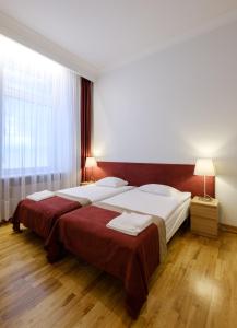 a bedroom with two beds and a large window at Hotel Metropolis in Kaunas