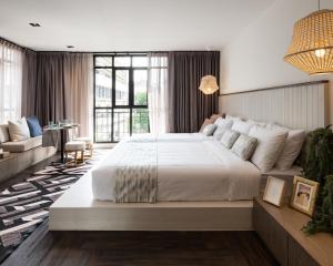 a bedroom with a large white bed and a couch at Warm Window Silom in Bangkok