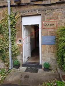 een deur met een rode pijl die naar een kluis wijst bij Modern, Cosy Apartment In Bearsden with Private Parking in Glasgow