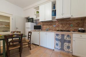 ヴィッラノーヴァ・ディ・オストゥーニにあるBrezza di Mare - Sea Breezeの白いキャビネット、テーブルと椅子付きのキッチンが備わります。