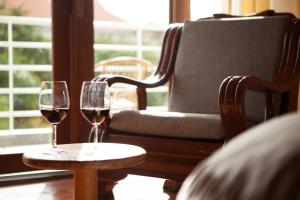 two glasses of wine on a table next to a chair at iRoHa Garden Hotel & Resort in Phnom Penh