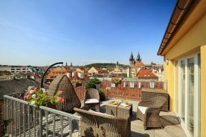 einen Balkon mit Korbstühlen und Stadtblick in der Unterkunft Grand Hotel Bohemia in Prag