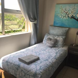a bed with two pillows on top of it at Bay Breeze Guesthouse in Gordonʼs Bay