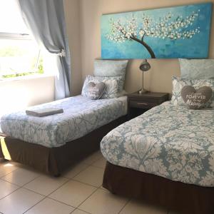 a bedroom with two beds and a window at Bay Breeze Guesthouse in Gordonʼs Bay