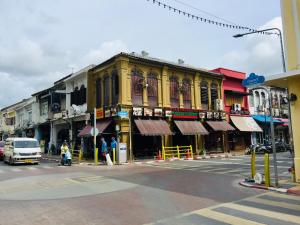 a yellow building on a city street with a street at Phuket Sunny Hostel in Phuket Town