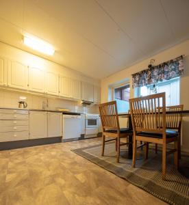 uma cozinha com armários brancos e uma mesa e cadeiras em Abisko Hostel em Abisko
