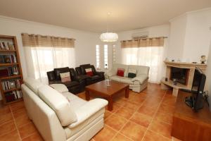 Una sala de estar con muebles blancos y chimenea. en Casa Antonio, en Armação de Pêra