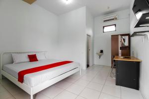 a bedroom with a white bed with a red blanket at RedDoorz @ Jagakarsa 2 in Jakarta
