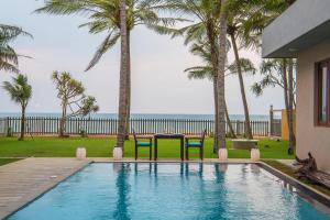 a swimming pool with two chairs and palm trees at Jetwing Villa 700 in Bentota