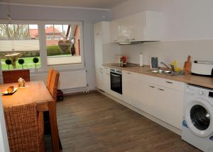 a kitchen with white cabinets and a table and a sink at Ferienwohnung Landliebe in Leer