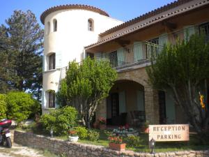 un bâtiment blanc avec un panneau devant lui dans l'établissement Logis du Comte, à Suze-la-Rousse