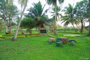 a park with rocks in the grass with palm trees at Lake Edge Holiday Inn in Tissamaharama