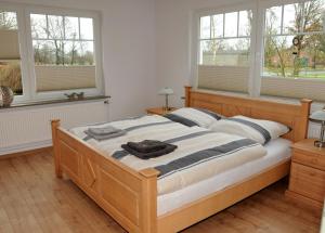 a bedroom with a large wooden bed with windows at Ferienwohnung Landliebe in Leer