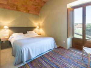 a bedroom with a white bed and a large window at Apartamentos en la Rectoria de Regencós in Regencós +105 photos