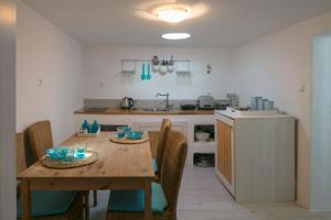 a kitchen with a wooden table with chairs and a kitchen with a sink at moonhouse in Skiathos