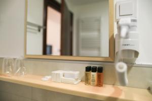 eine Badezimmerablage mit einem Spiegel und einigen Produkten darauf in der Unterkunft GARNI HOTEL ATRIUM in Nikšić + 28 Fotos