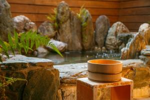 a small pot sitting on a stump next to a pond at Yawarano-yu MARUYA For women only in Ise
