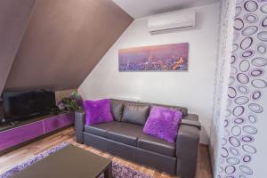 シャールヴァールにあるRubin Relax Apartmanのリビングルーム(ソファ、紫色の枕付)