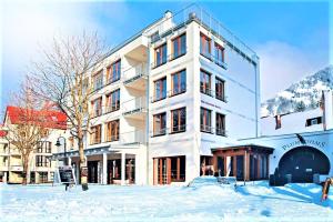 a large white building with snow on the ground at Plumbohms ECHT-HARZ-HOTEL in Bad Harzburg