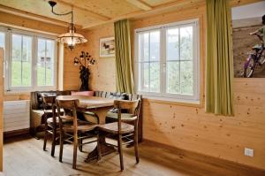ein Esszimmer mit einem Tisch, Stühlen und Fenstern in der Unterkunft Chalet Gletscherbach - GRIWA RENT AG in Grindelwald