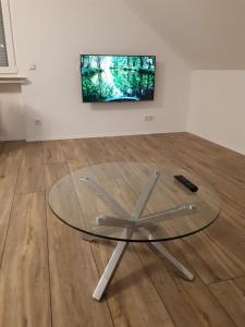 a glass table in a room with a television on a wall at Ferienwohnung Kreuder in Bergisch Gladbach