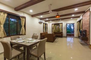 een eetkamer en een woonkamer met een tafel en stoelen bij SaffronStays Ekaant, Vikramgad - party-perfect pool villa with spacious lawn in Pālghar