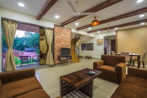 ein Wohnzimmer mit einem Sofa, Stühlen und einem TV in der Unterkunft SaffronStays Ekaant, Vikramgad - party-perfect pool villa with spacious lawn in Pālghar