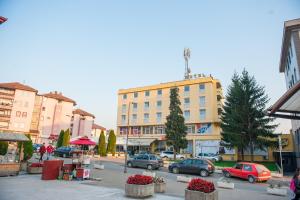 a city street with cars parked in front of a building at Prenoćište "NACIONAL" in Prnjavor