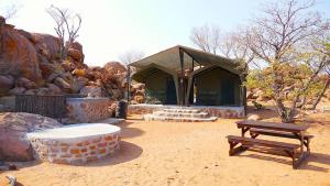 ein Gebäude mit einem Picknicktisch und einer Bank in der Unterkunft Madisa Camp in Kalkbron