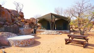 a building with a picnic table and a bench at Madisa Camp in Kalkbron