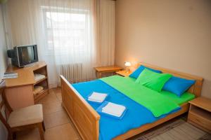 a bedroom with a blue and green bed and a television at Prenoćište "NACIONAL" in Prnjavor